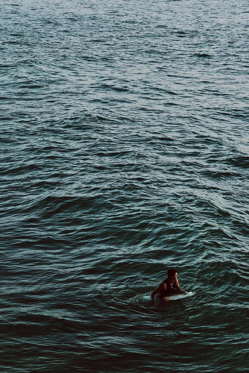 water man riding on surfboard on body of water during daytime ripple