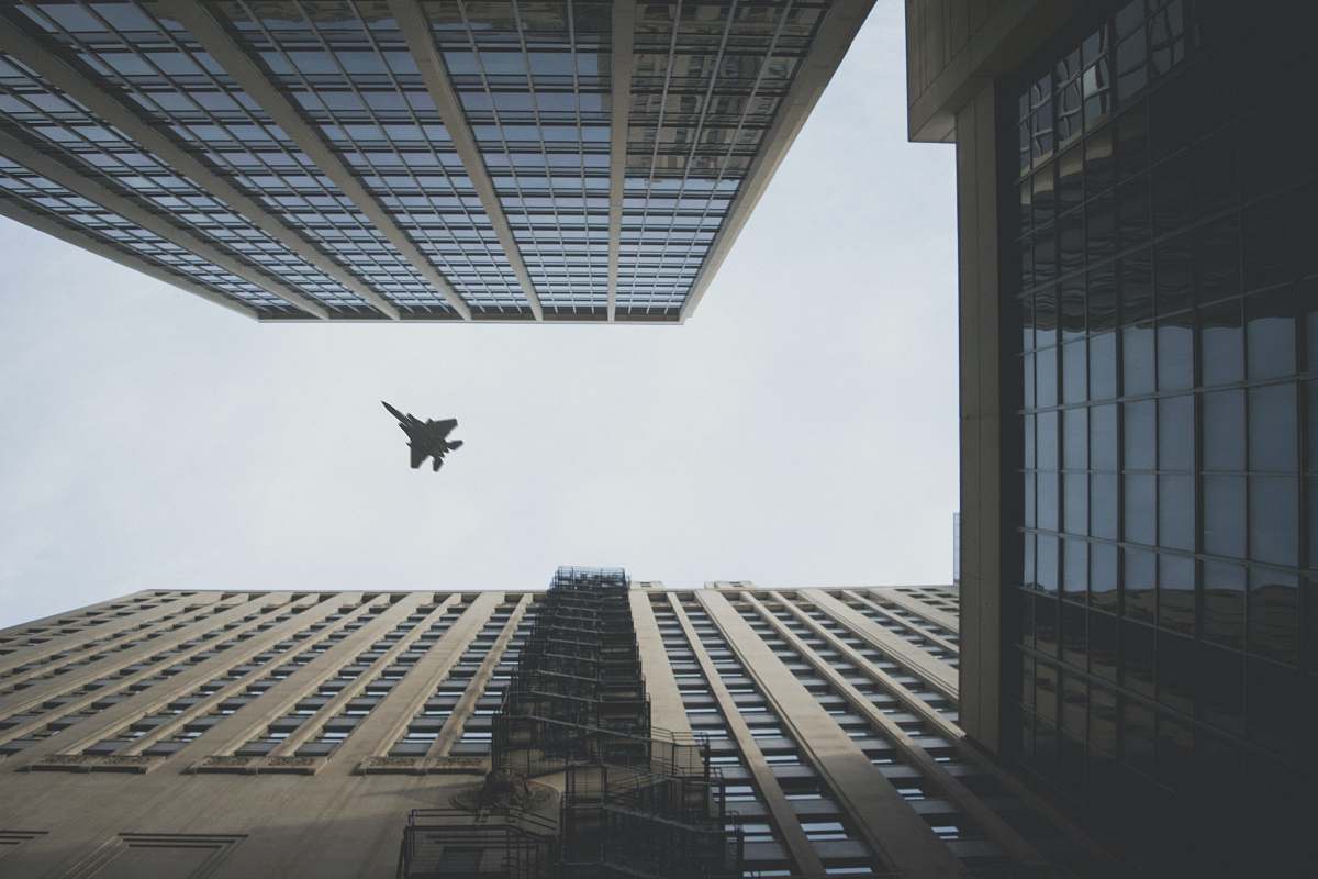 chicago worm's view photo of fighter jet flying above building building
