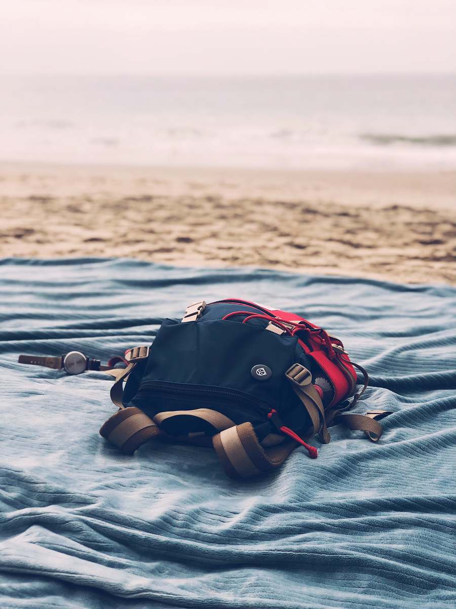person black bag on gray textile near seashore people