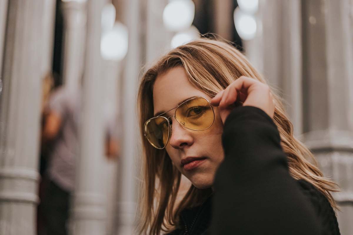 person focus of photo of woman holding her sunglasses people