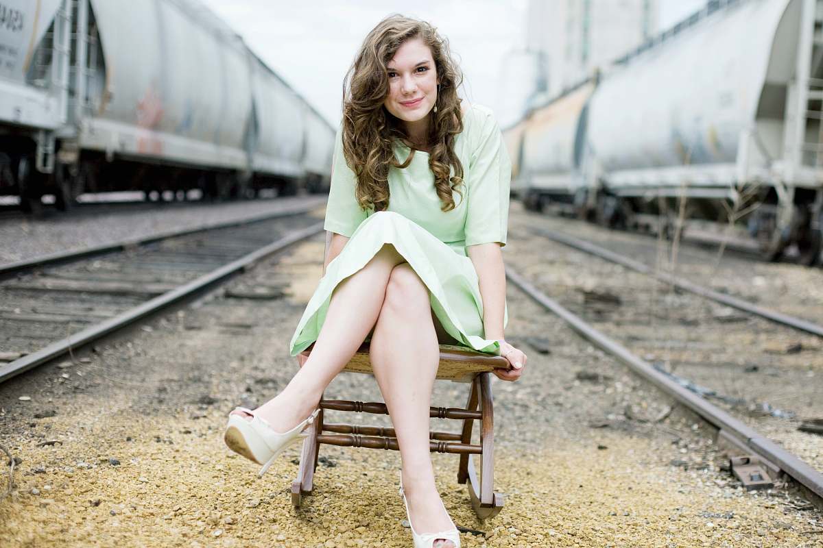 person girl sitting on chair between train tracks during day people