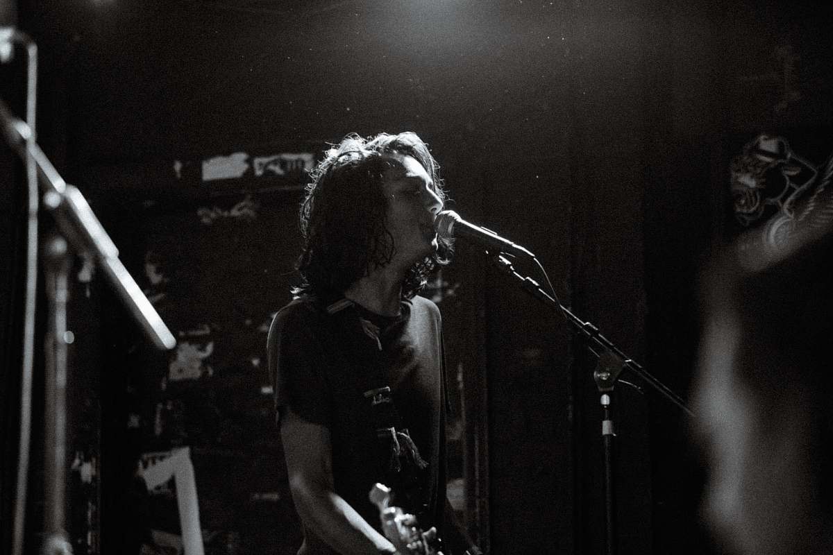 person greyscale photo of man singing while holding guitar black-and-white