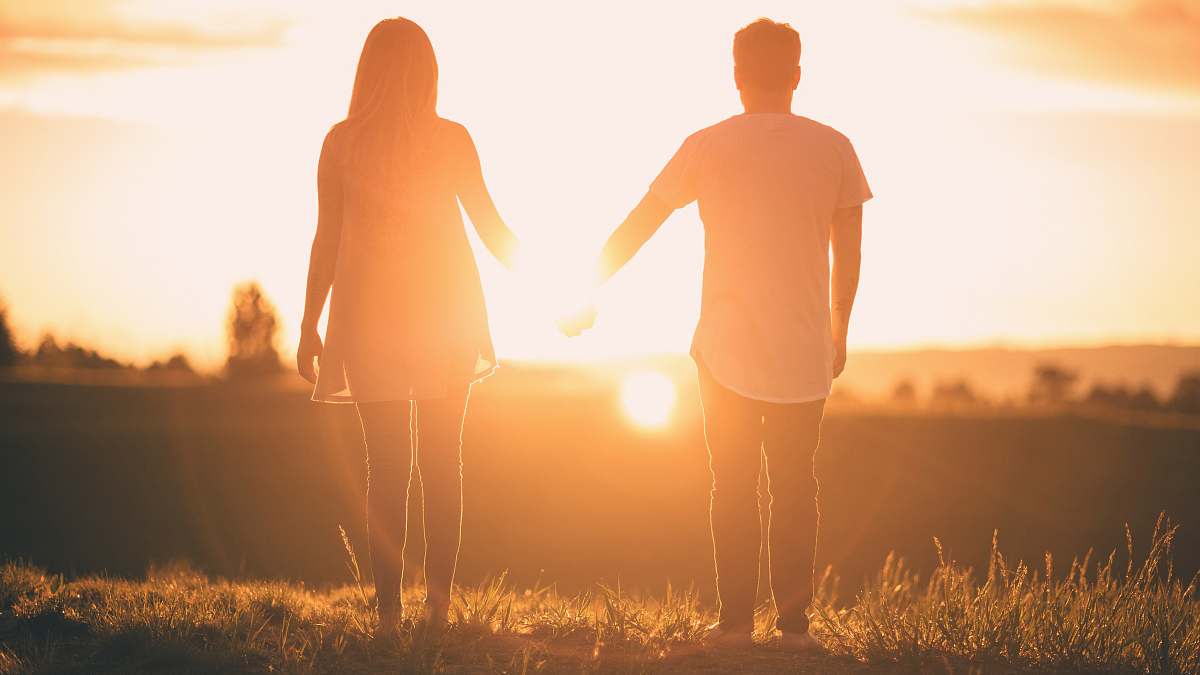 person man and woman holding hands white facing sunset people