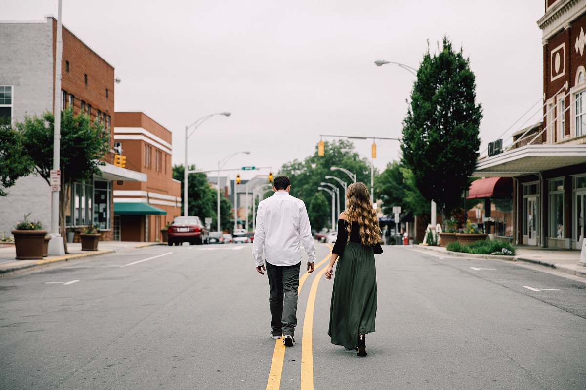 people man and woman walking in the middle of the road plant