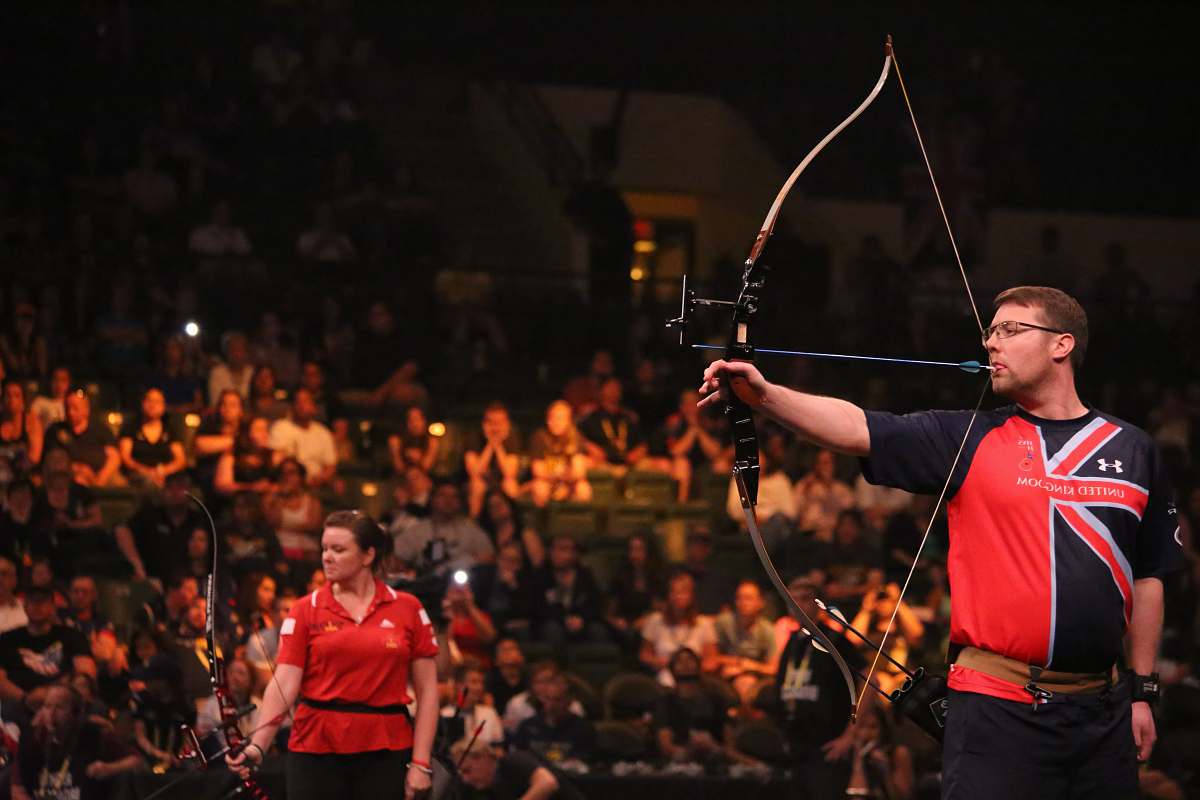 person man doing archery near woman holding bow bow
