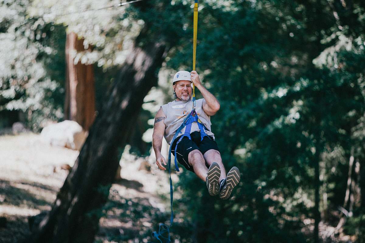 person man hanging and wearing harness during daytime apparel