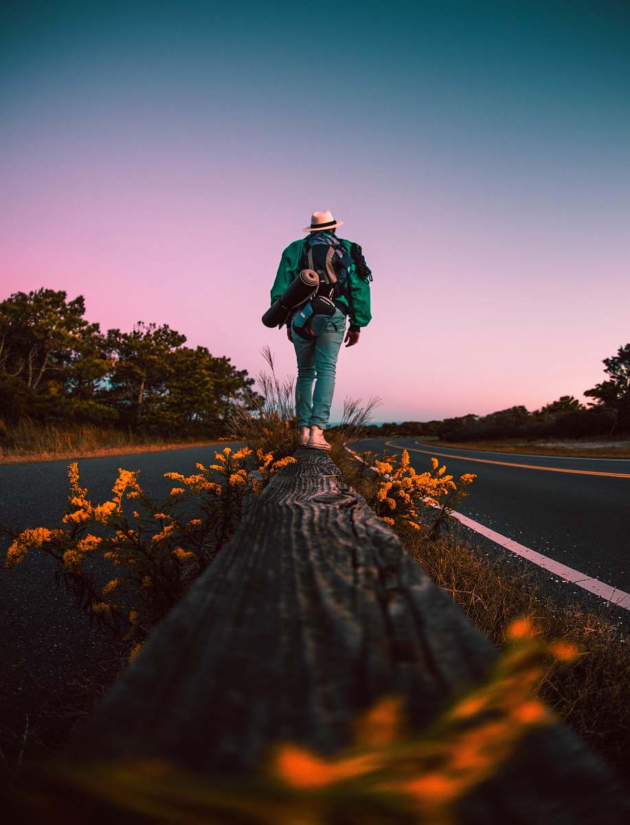 person man in black jacket and blue denim jeans standing on road during daytime road