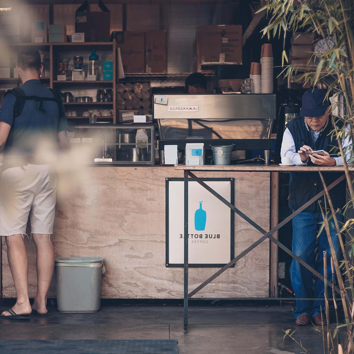 people man leaning on table in front of coffee store person