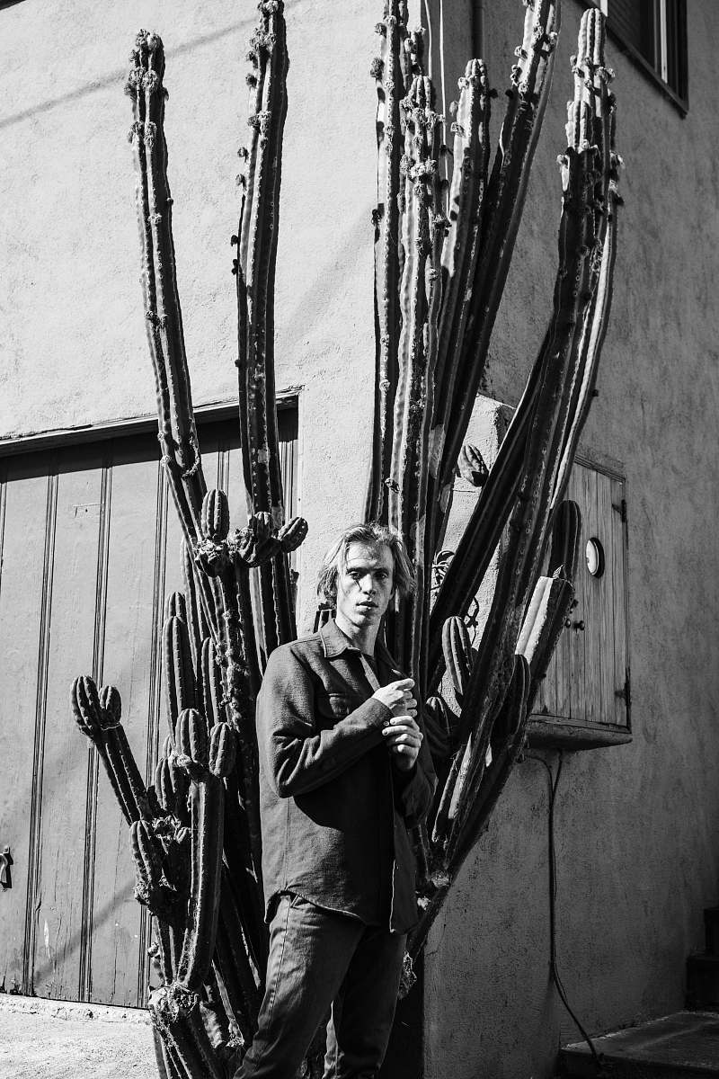 people man standing beside cactus black-and-white