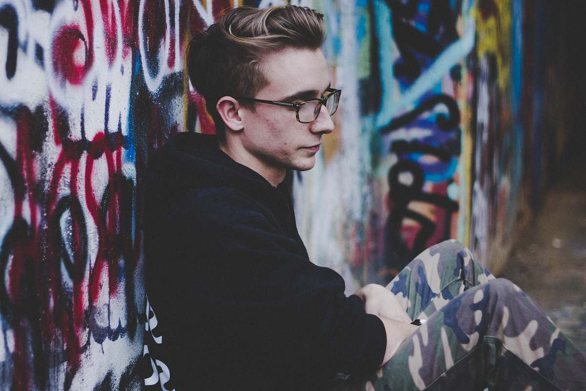 people man wearing black hoodie and leaning on wall graffiti