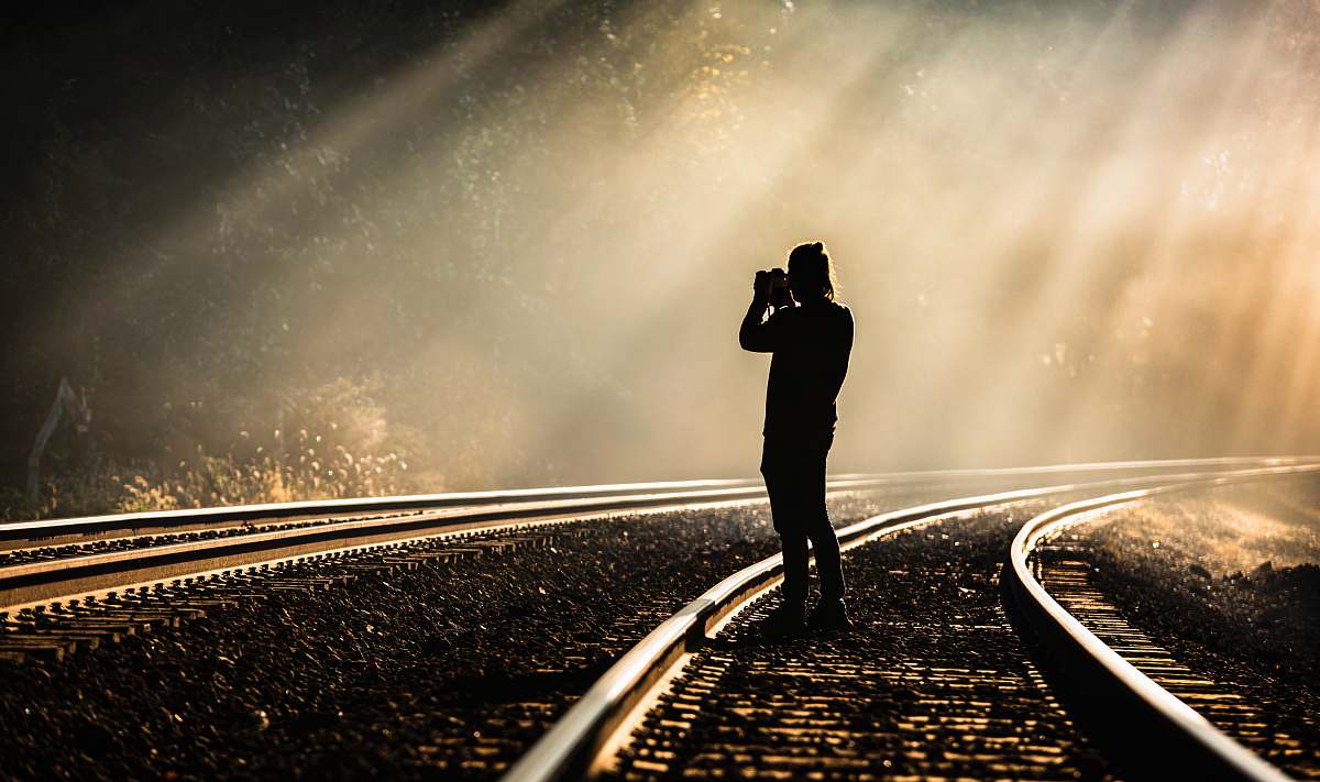 person person holding camera standing on train track while taking photo nashville