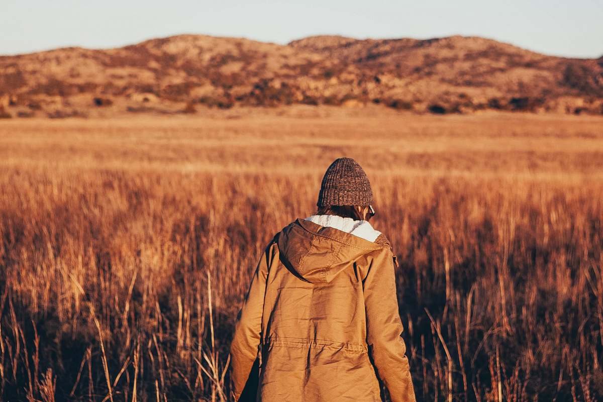 person person wearing jacket walking in brown grass field people