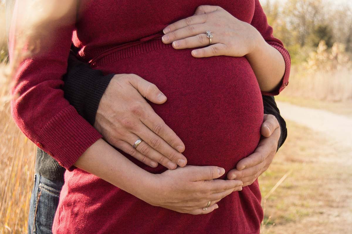 person pregnant woman standing behind the man holding tummy people