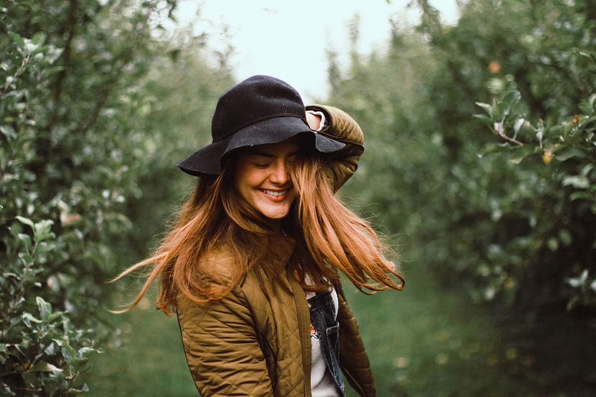 person selective focus photography of woman holding her hat while smiling people
