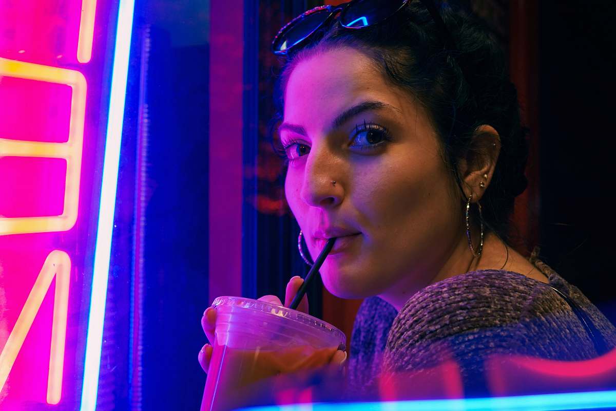 person woman drinking iced coffee looking side accessories