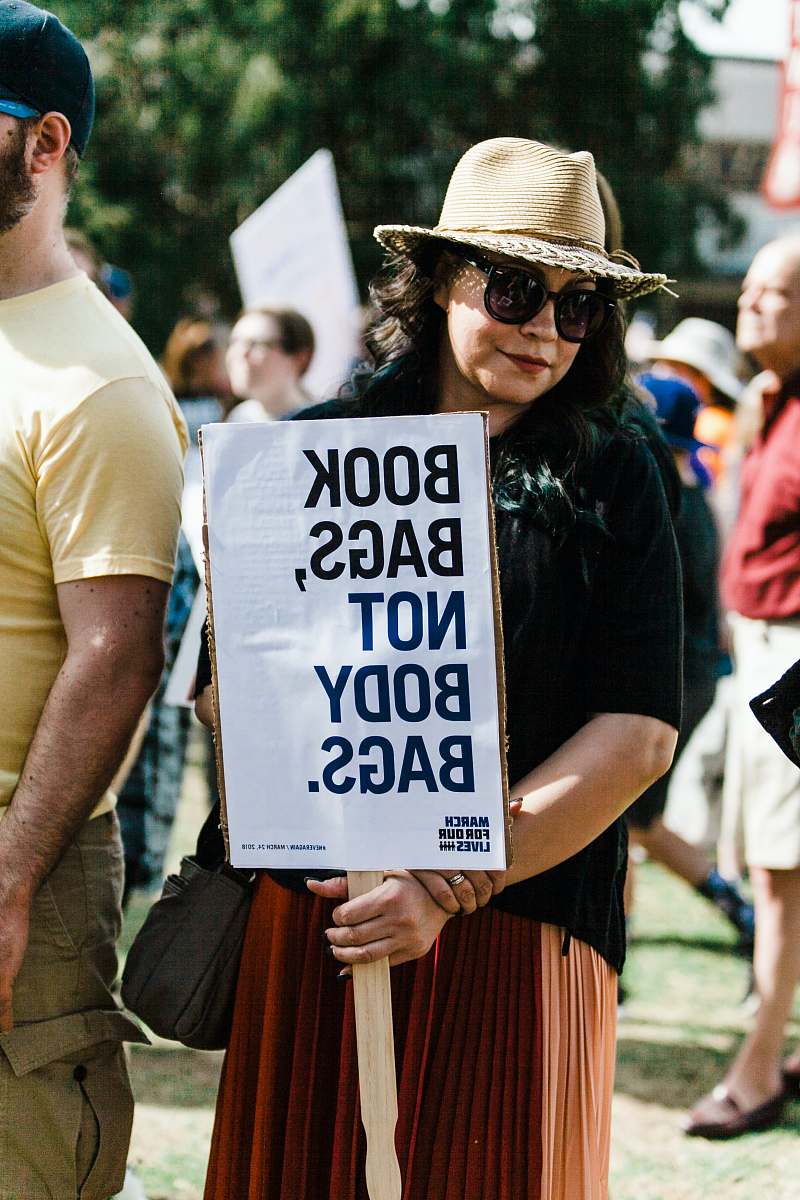 person woman holding book bags, not body bags. signboard people