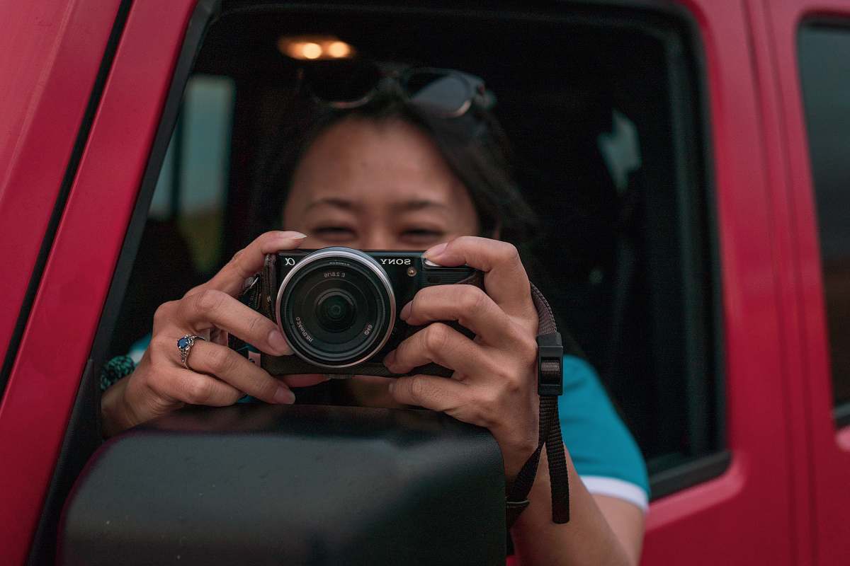 person woman holding DSLR camera in red vehicle camera