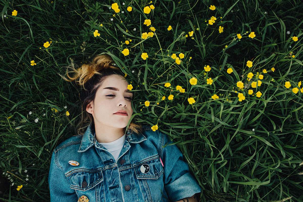 people woman in blue chambray jacket lying on green grass person