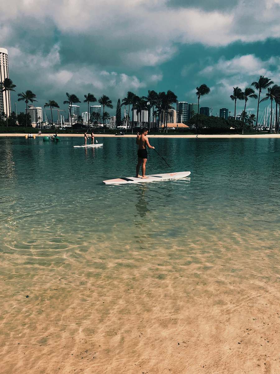 person woman in red dress standing on white surfboard on beach during daytime oars
