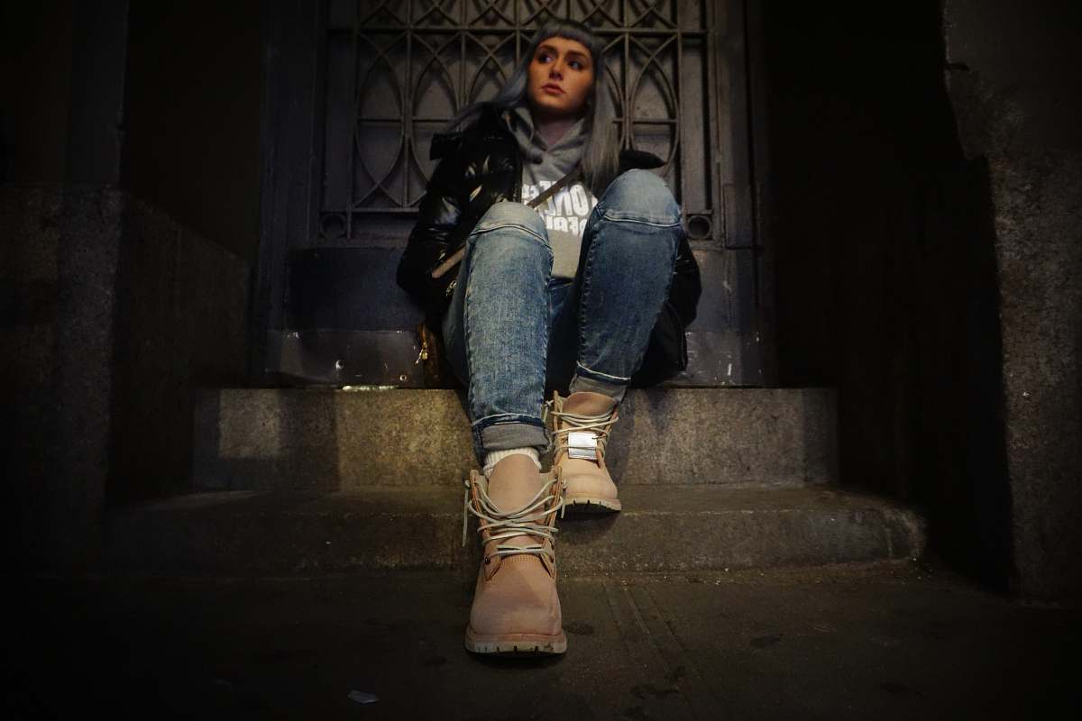 person woman sitting on top of gray concrete stair near door people