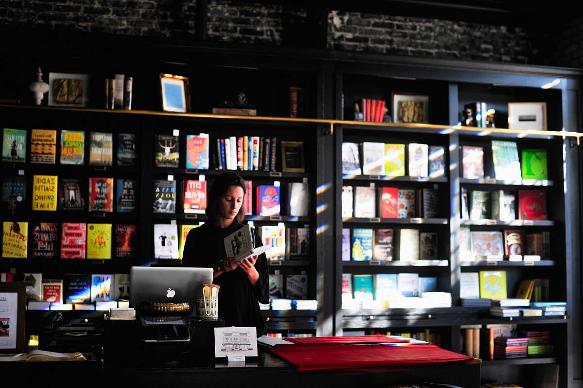 person woman standing in front of book shelf people