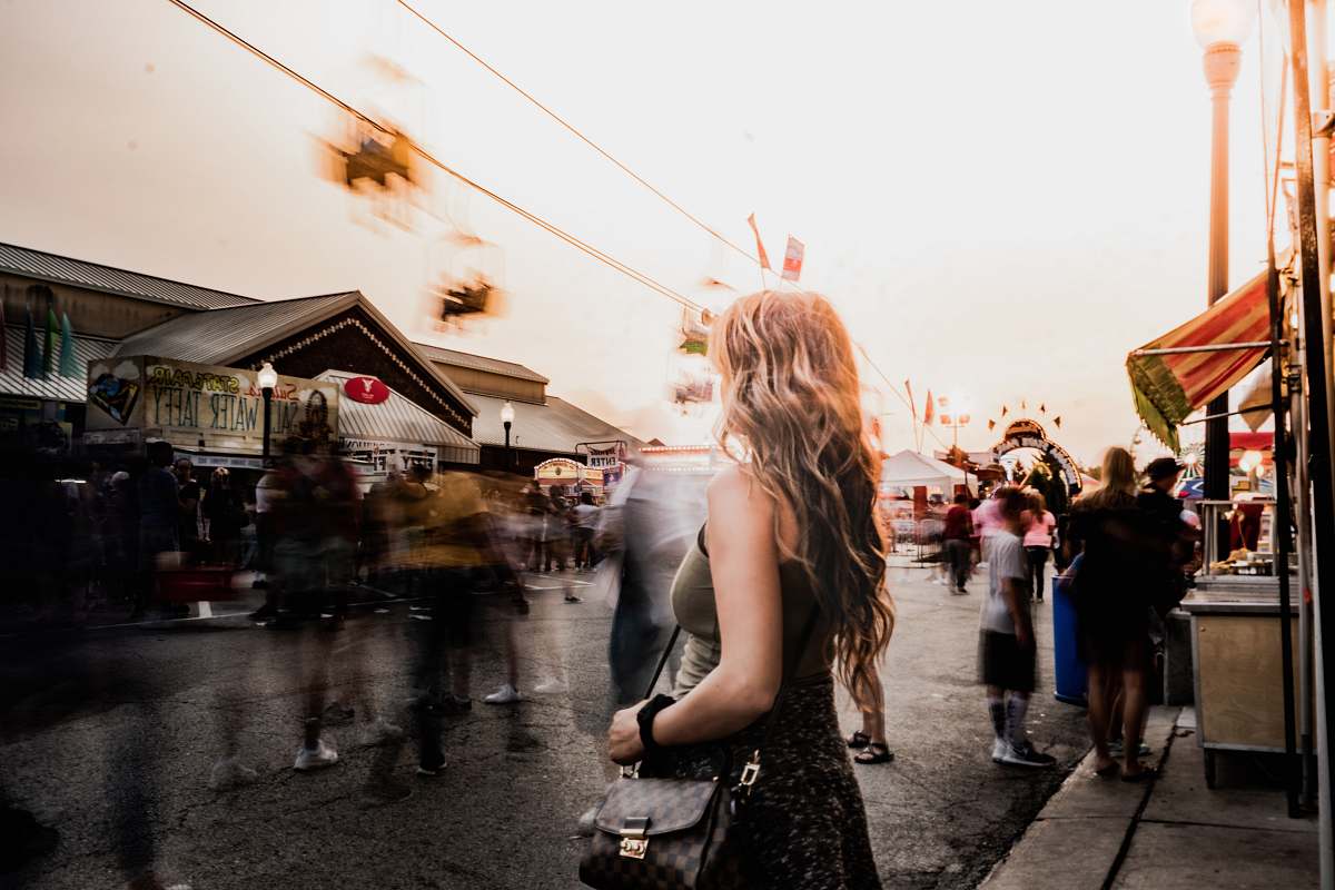 person woman standing on road side in front of crowd people
