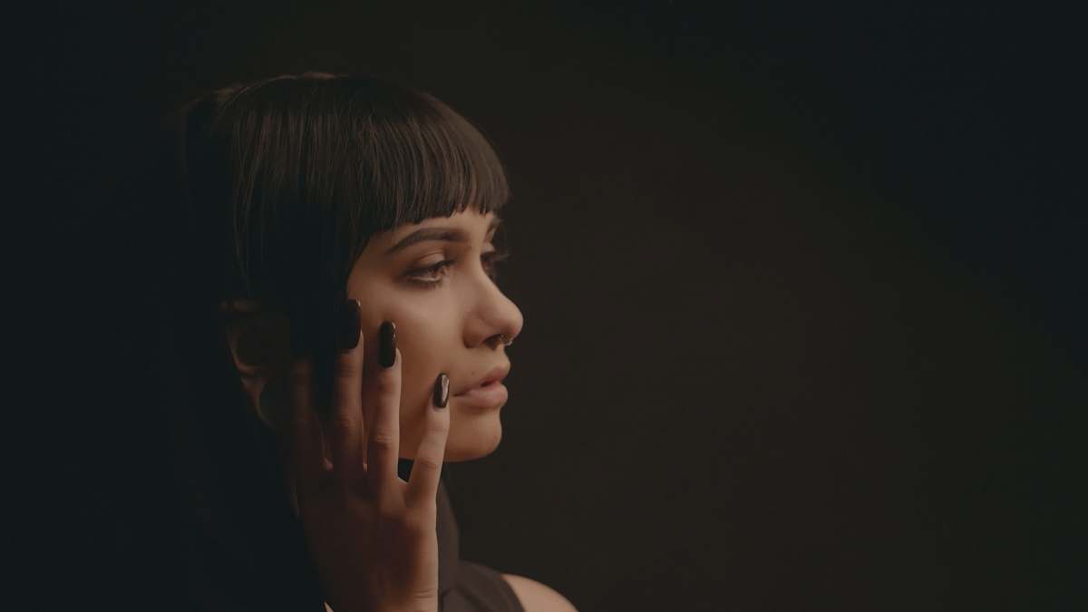 people woman touch her cheek in dim light person
