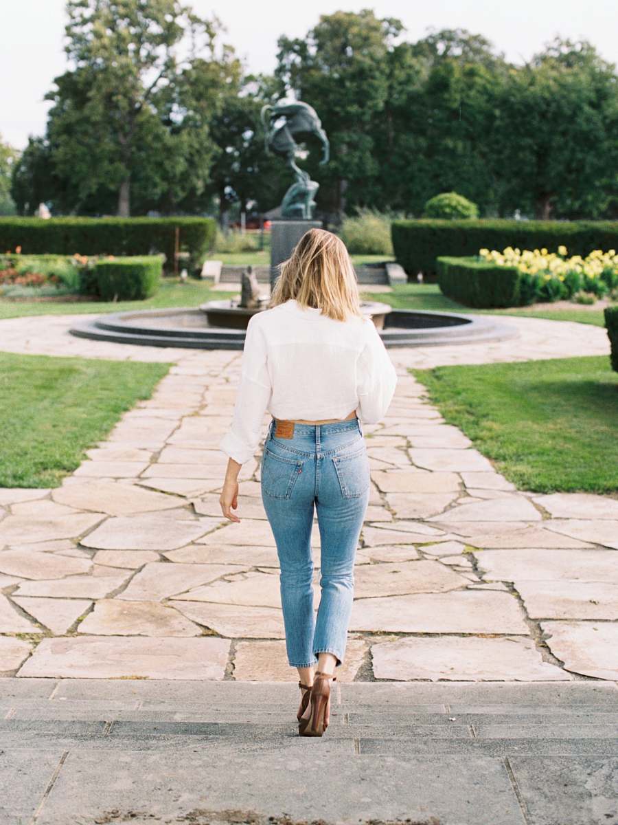denim woman walking near black water fountain jeans