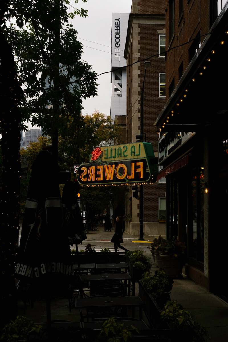 person woman walking under La Salle Flowers neon signage chicago