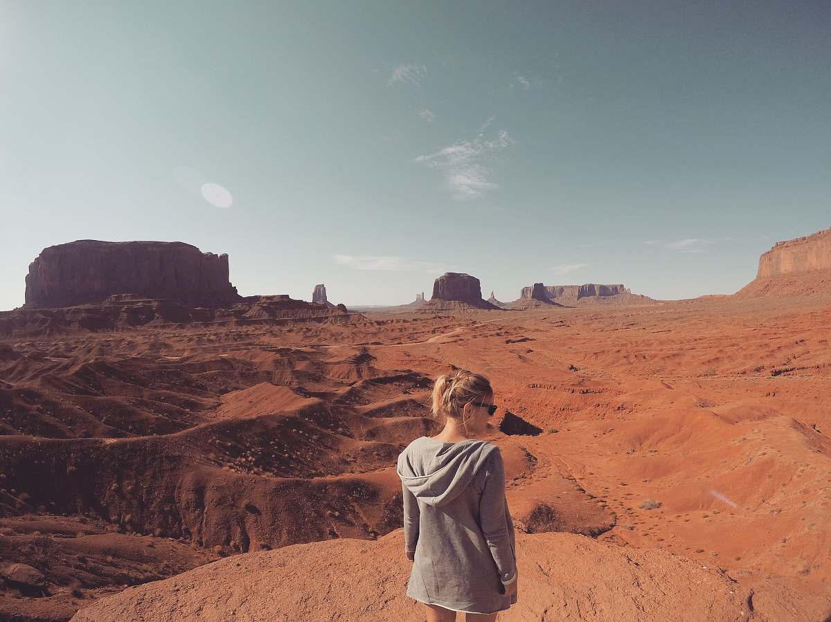 people woman wearing gray hooding looking at Monument Valley at daytime desert