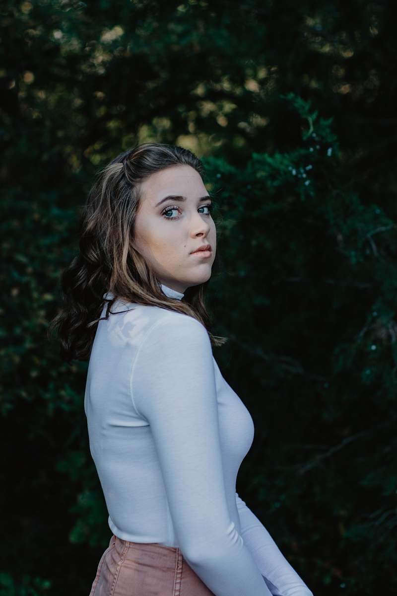 person woman wearing white turtleneck long-sleeved shirt and brown bottoms near green-leafed plants during daytime people