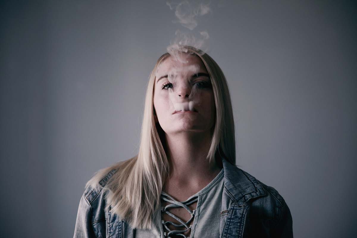 person woman wears gray top smokes on mouth people