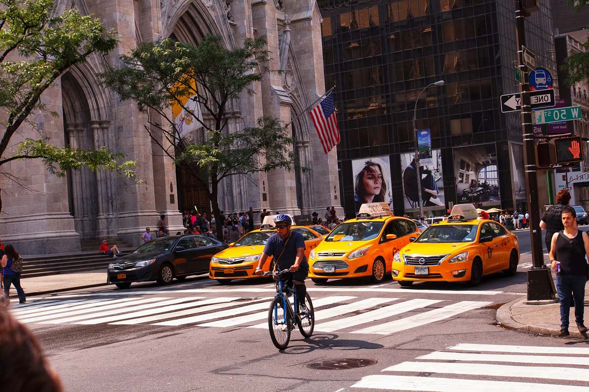 person yellow taxi cab on the street during daytime asphalt