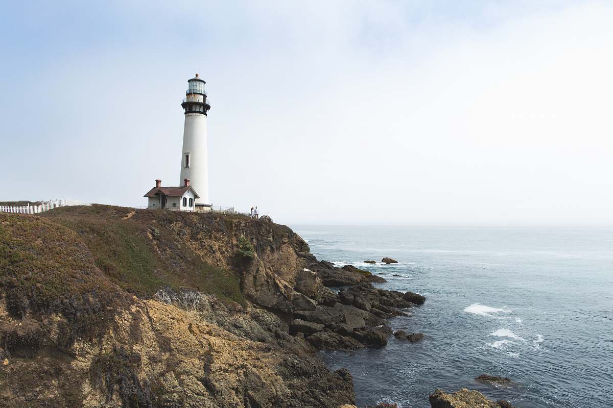 beacon white lighthouse on hill near ocean coast