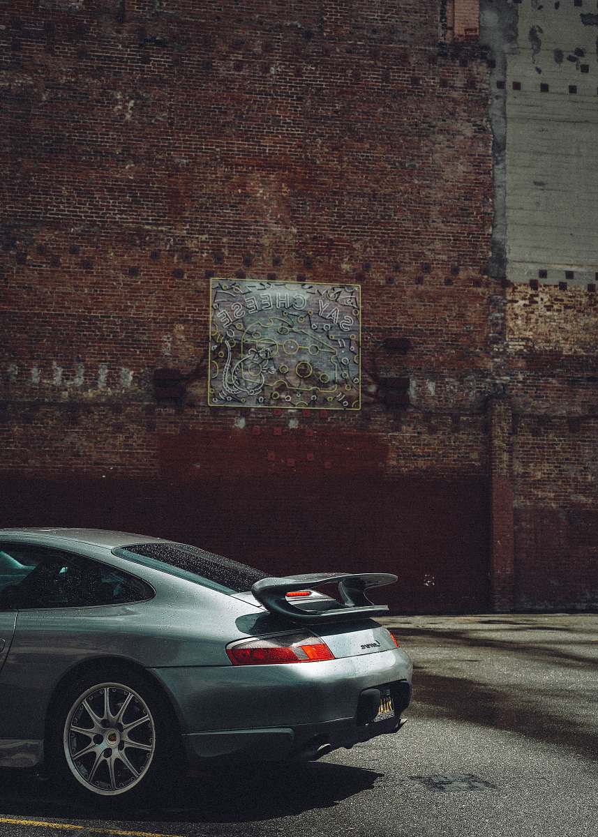 spoke silver sedan parked beside brown brick wall automobile