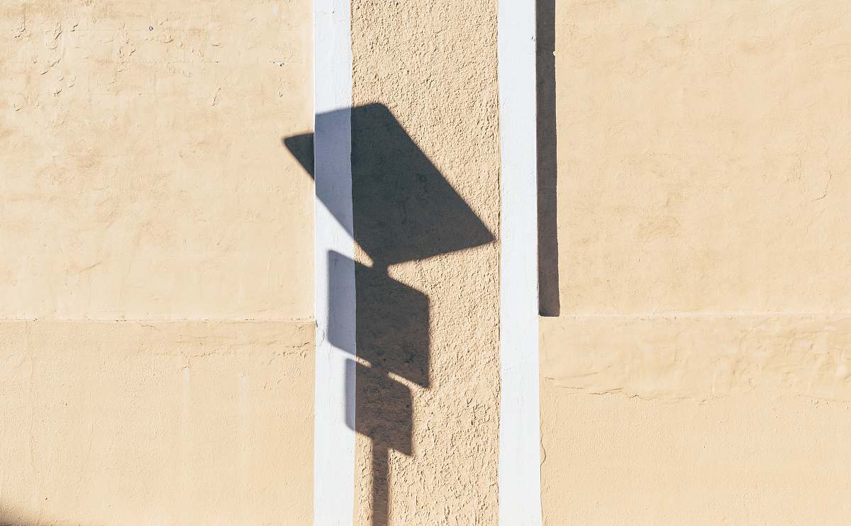 This captivating image features an artistic shadow of a street sign casting elegant letters on a textured wall. The interplay of light and shadow creates a unique visual representation, perfect for urban-themed projects, graphic design, and creative storytelling. Ideal for use in advertising, blogs, and social media content that explores themes of communication, direction, and the urban environment.