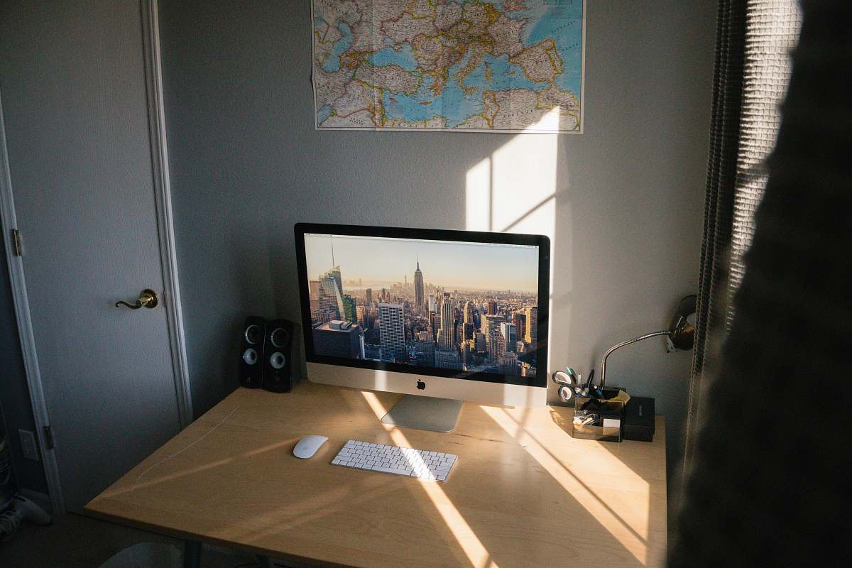 screen turned on silver iMac on beige wooden desk electronics