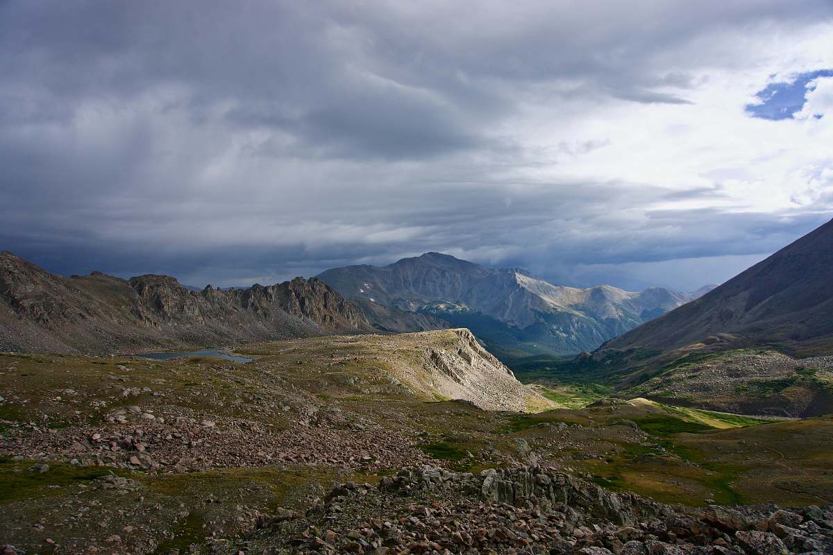 peak green and gray mountains under cloudy sky field