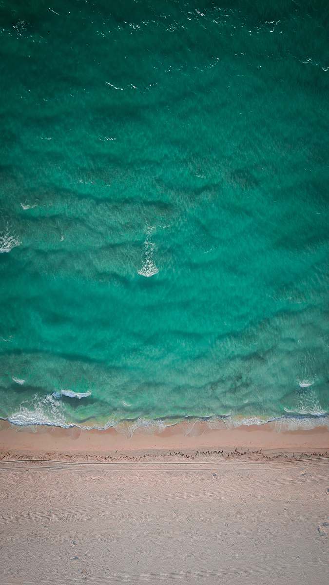 beach aerial photo of green body of water at daytime coast