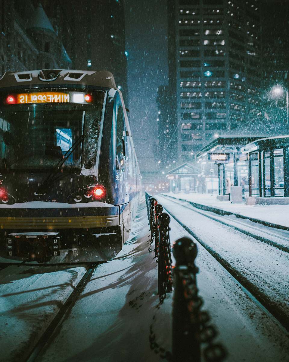 outdoors black and brown train near the building during nighttime snow