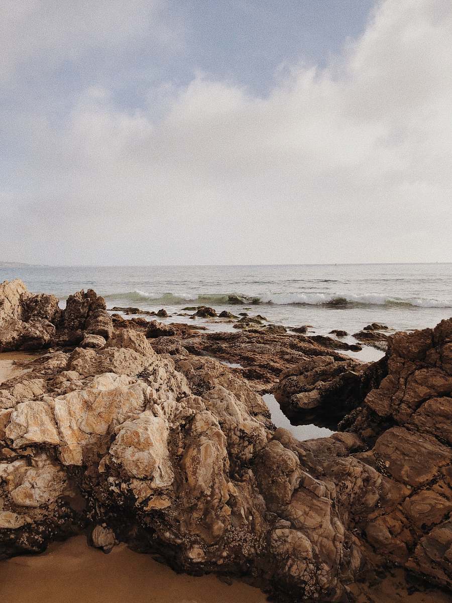 promontory brown rocks beside beach cliff