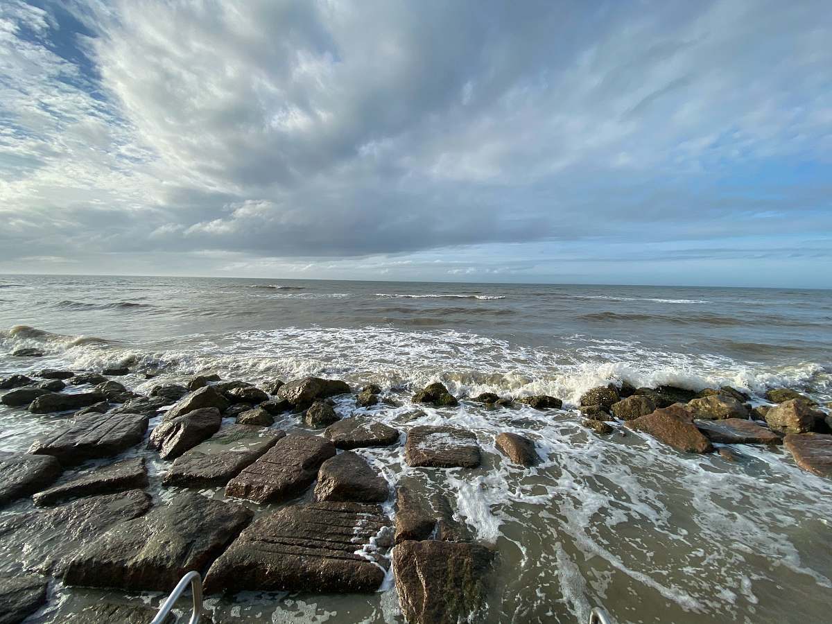 ocean brown rocks on sea shore under white clouds and blue sky during daytime outdoors
