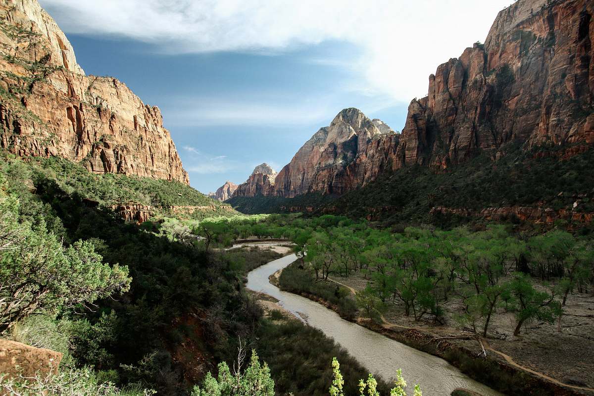 mountain flowing river near tall trees viewing mountain under blue and white skies outdoors