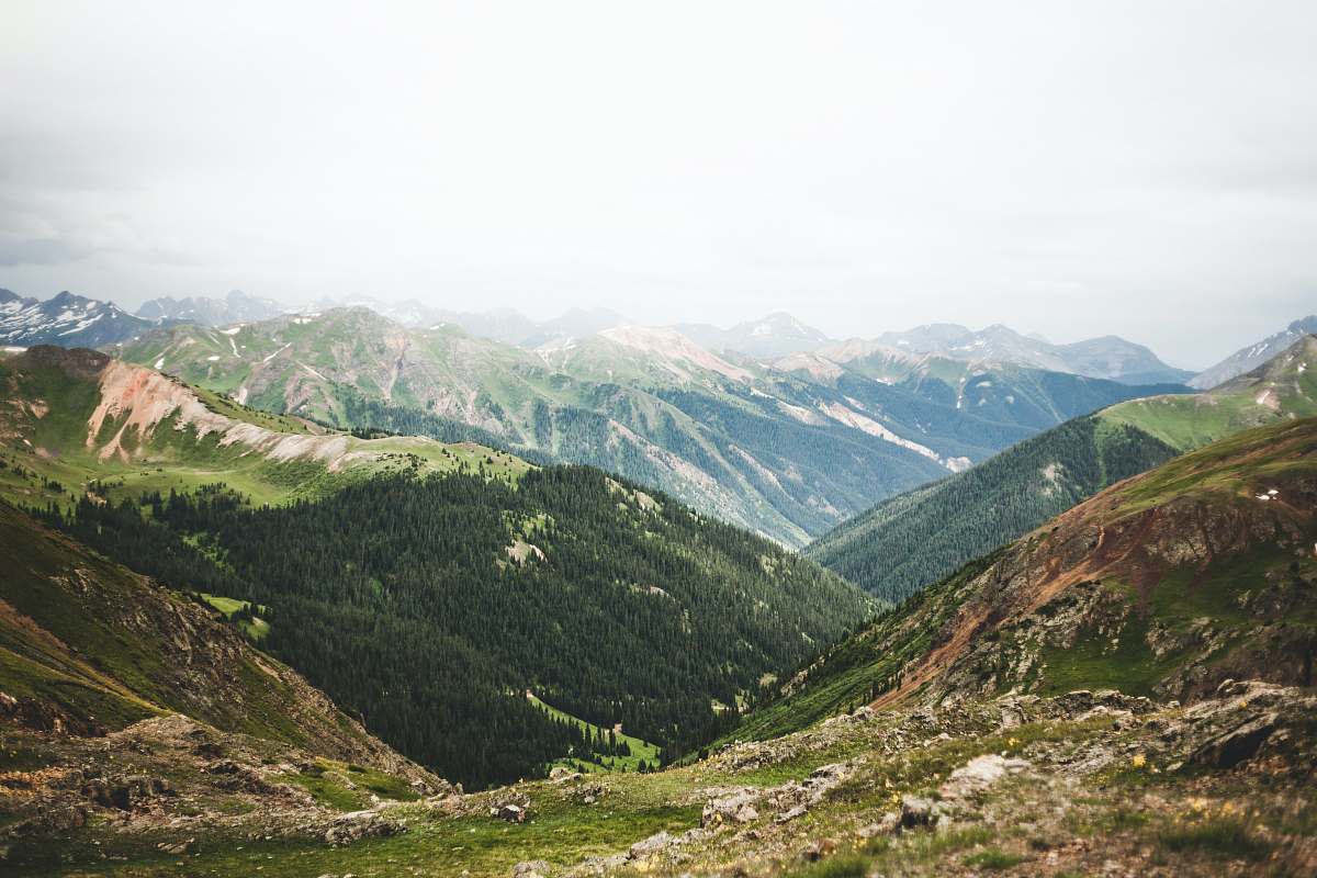 mountain grass field near mountain range under cumulus clouds mountain range