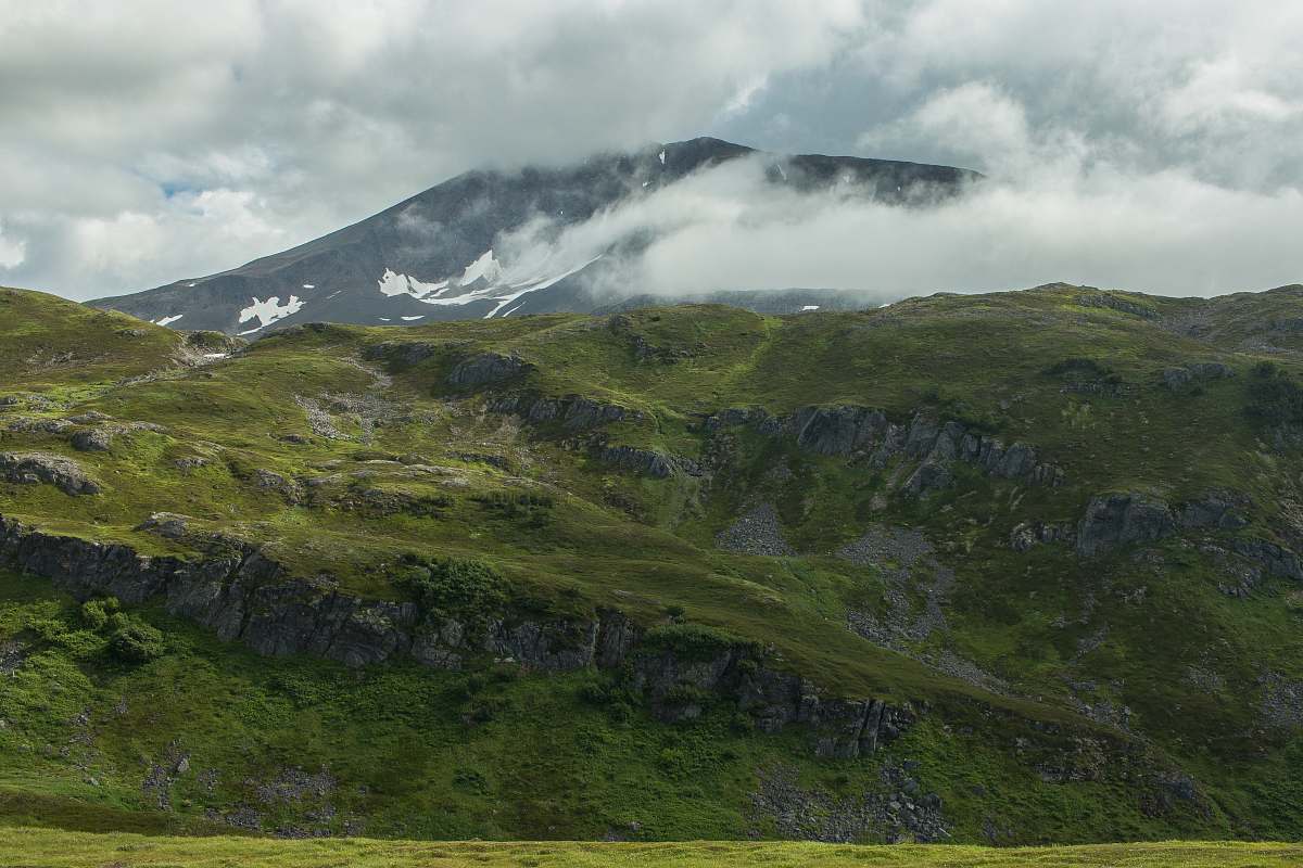 mountain green mountain under cloudy sky during daytime crest