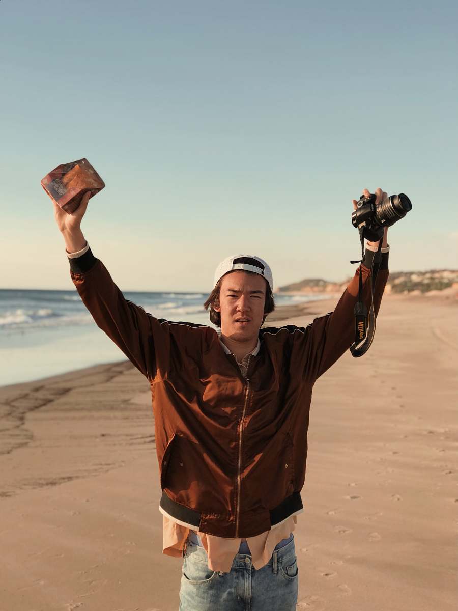 outdoors man holding DSLR camera near body of water during daytime soil