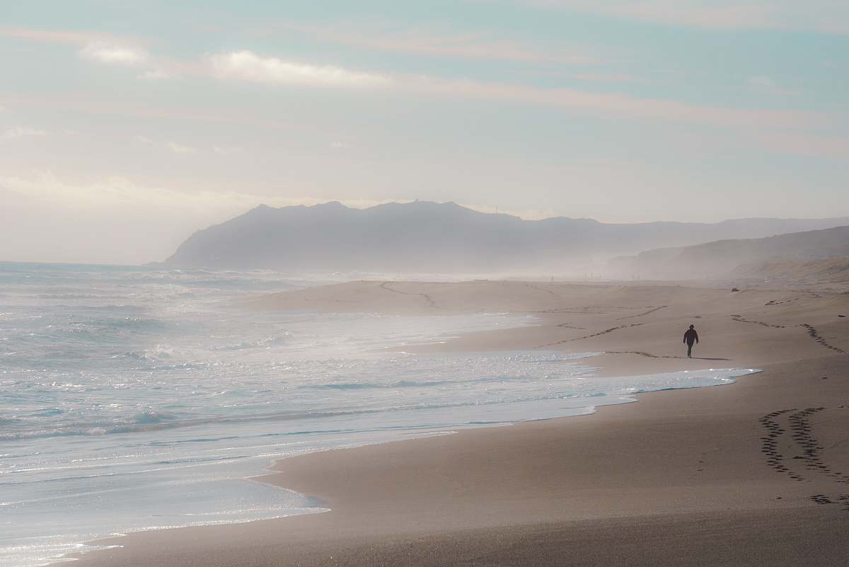 person man walking beside body of water grey