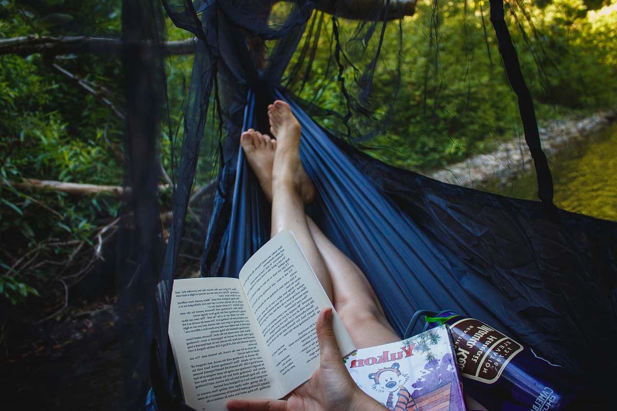outdoors person holding book hammock