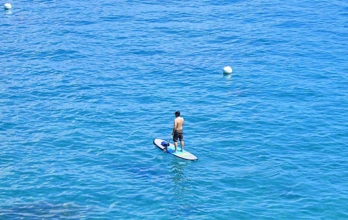 ocean woman in black bikini riding on blue surfboard during daytime water