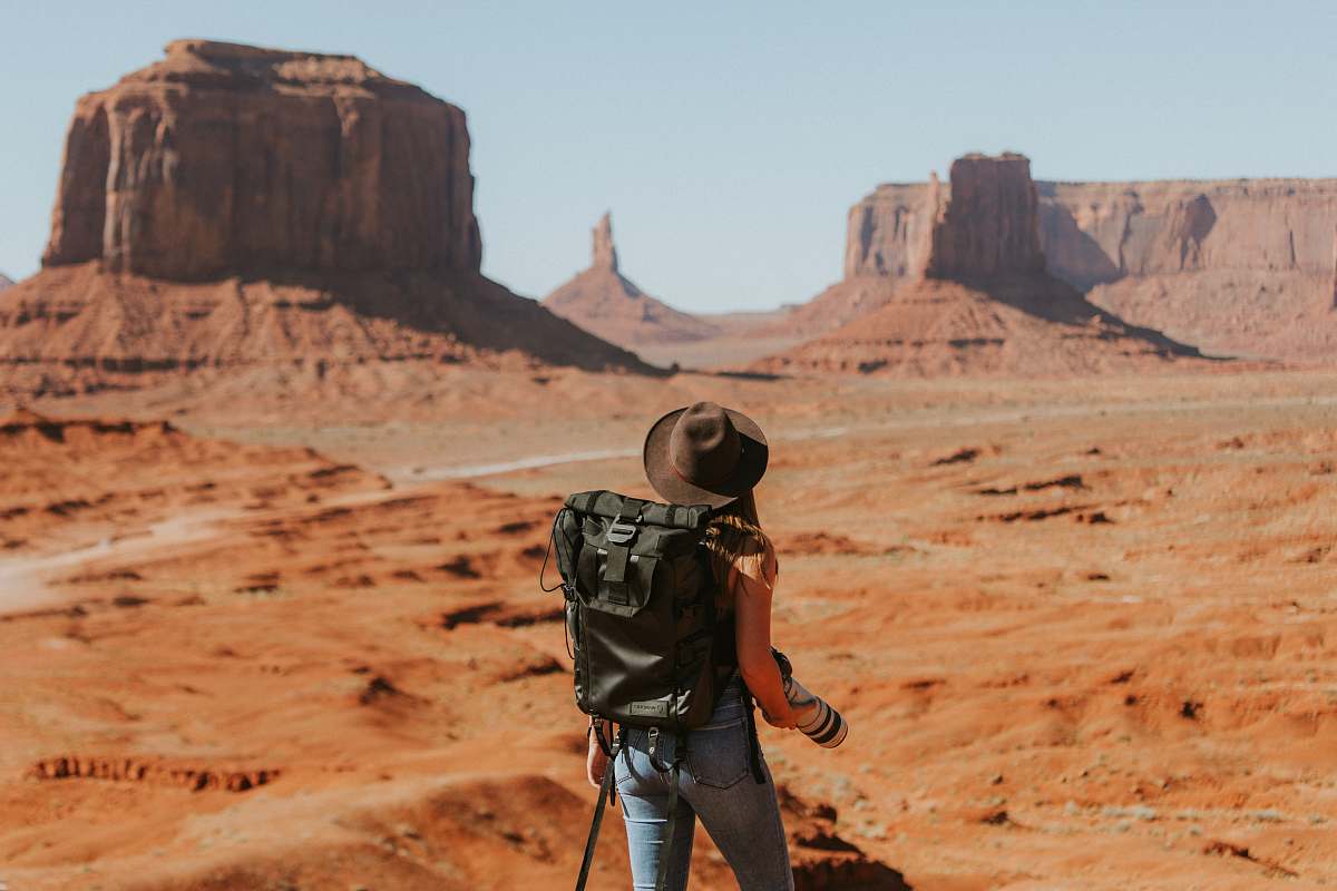 desert woman with black backpack standing on brown dessert outdoors